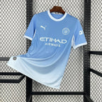 Maillot Manchester City Domicile 2026/2027 sur fond grillagé
